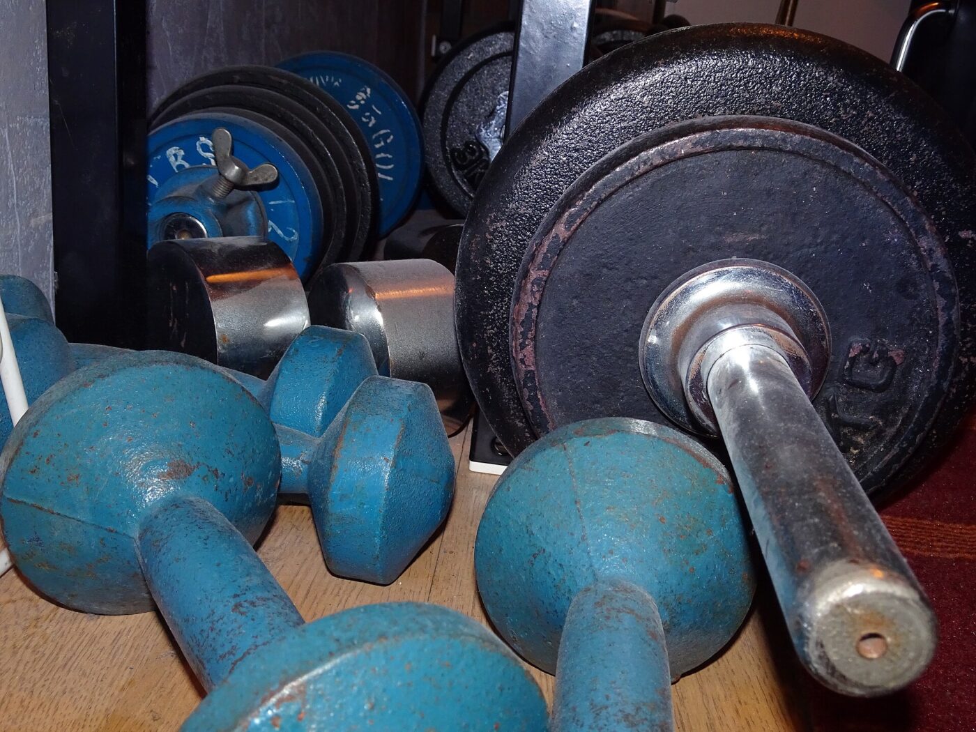 Blue dumbbells and a barbell among weight training gear.