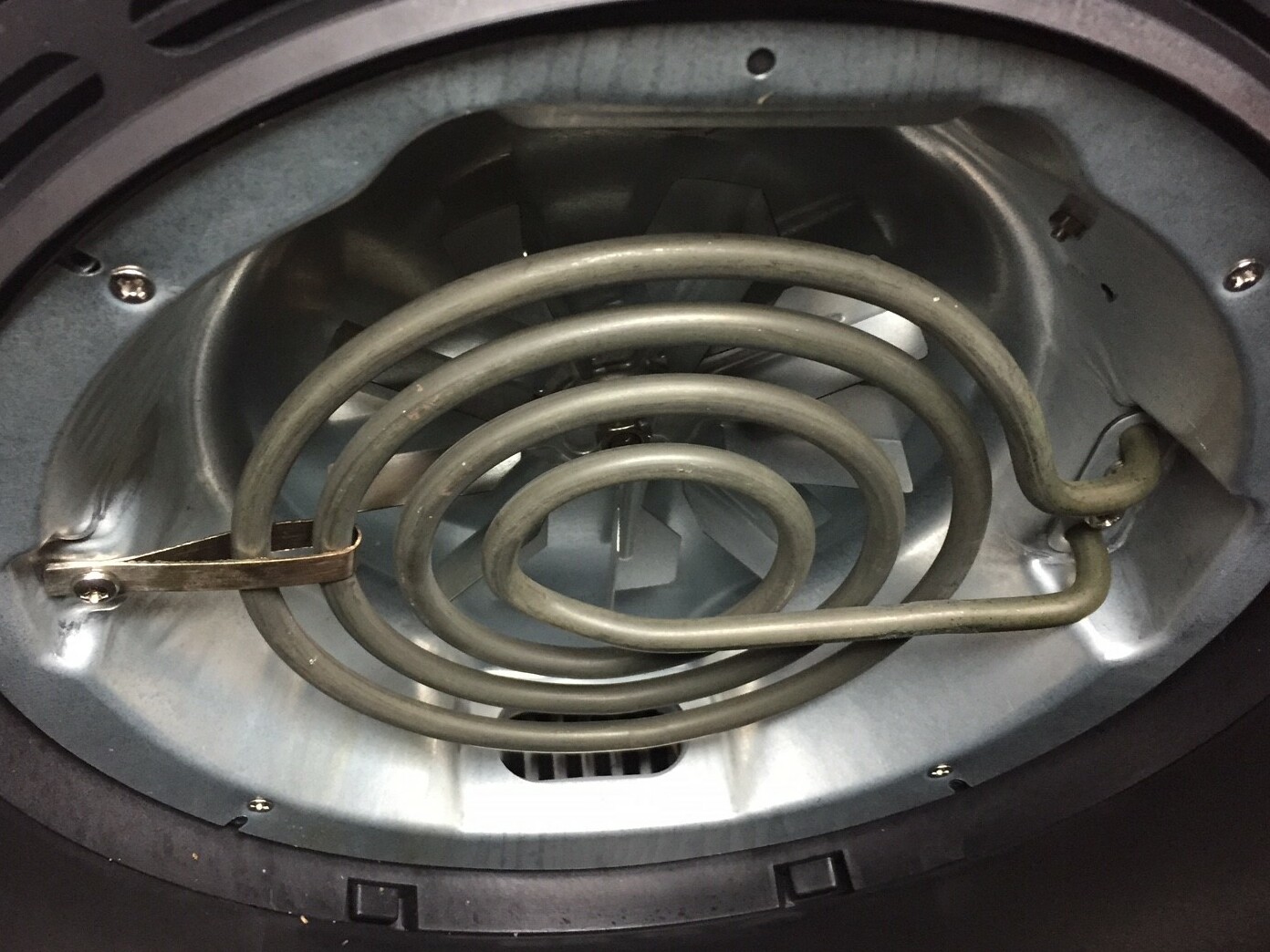 Under the lid: the spiral heating element that sits just above the fan. That is the whole machine, and it is why an air fryer is audible over a television.