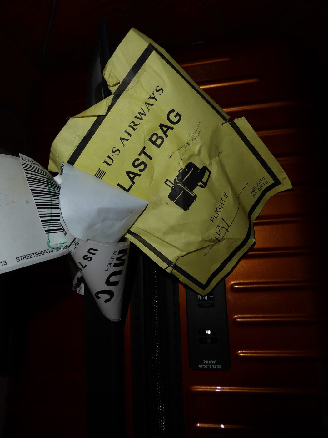 A yellow airline baggage tag reading Last Bag, clipped to a bag strap.