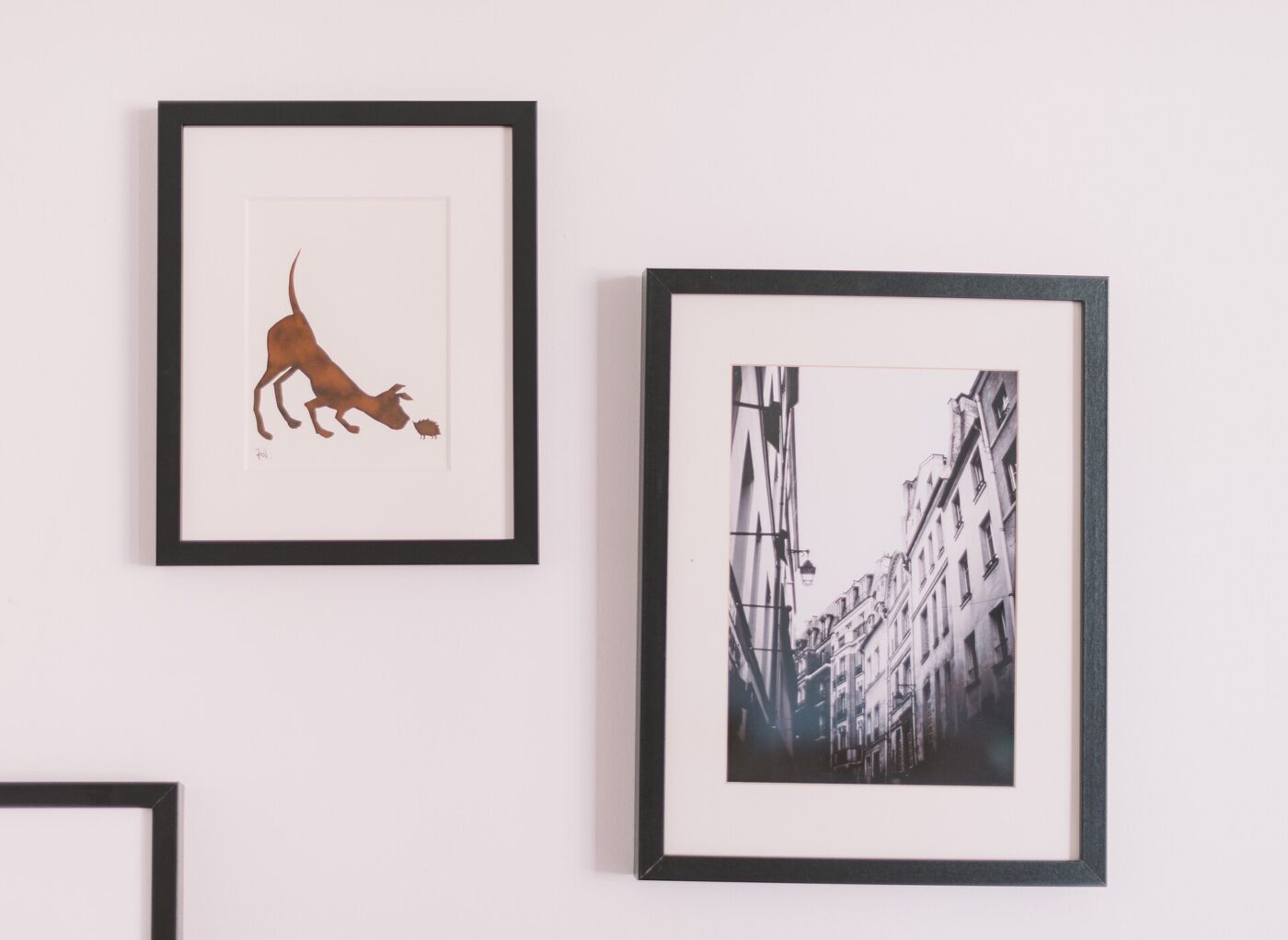 Two framed prints hanging on a plain wall.