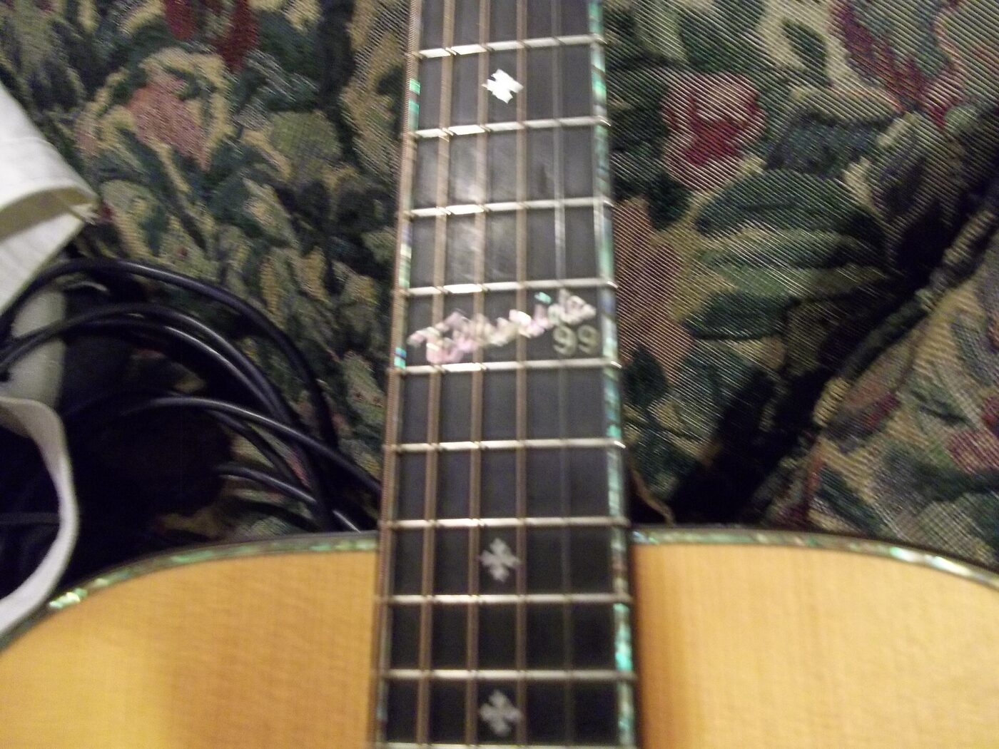 Close-up of an acoustic guitar's fretboard, frets and strings.