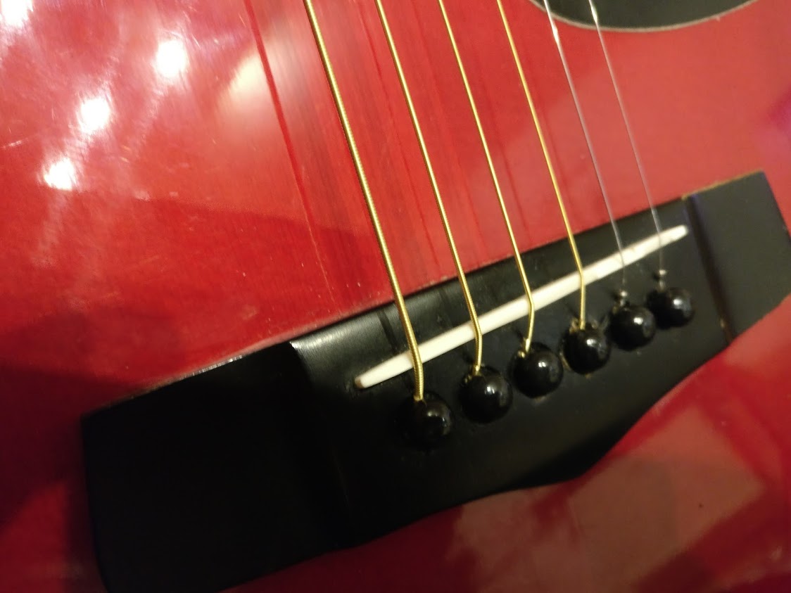 The bridge and saddle of an acoustic guitar, where string height is set.