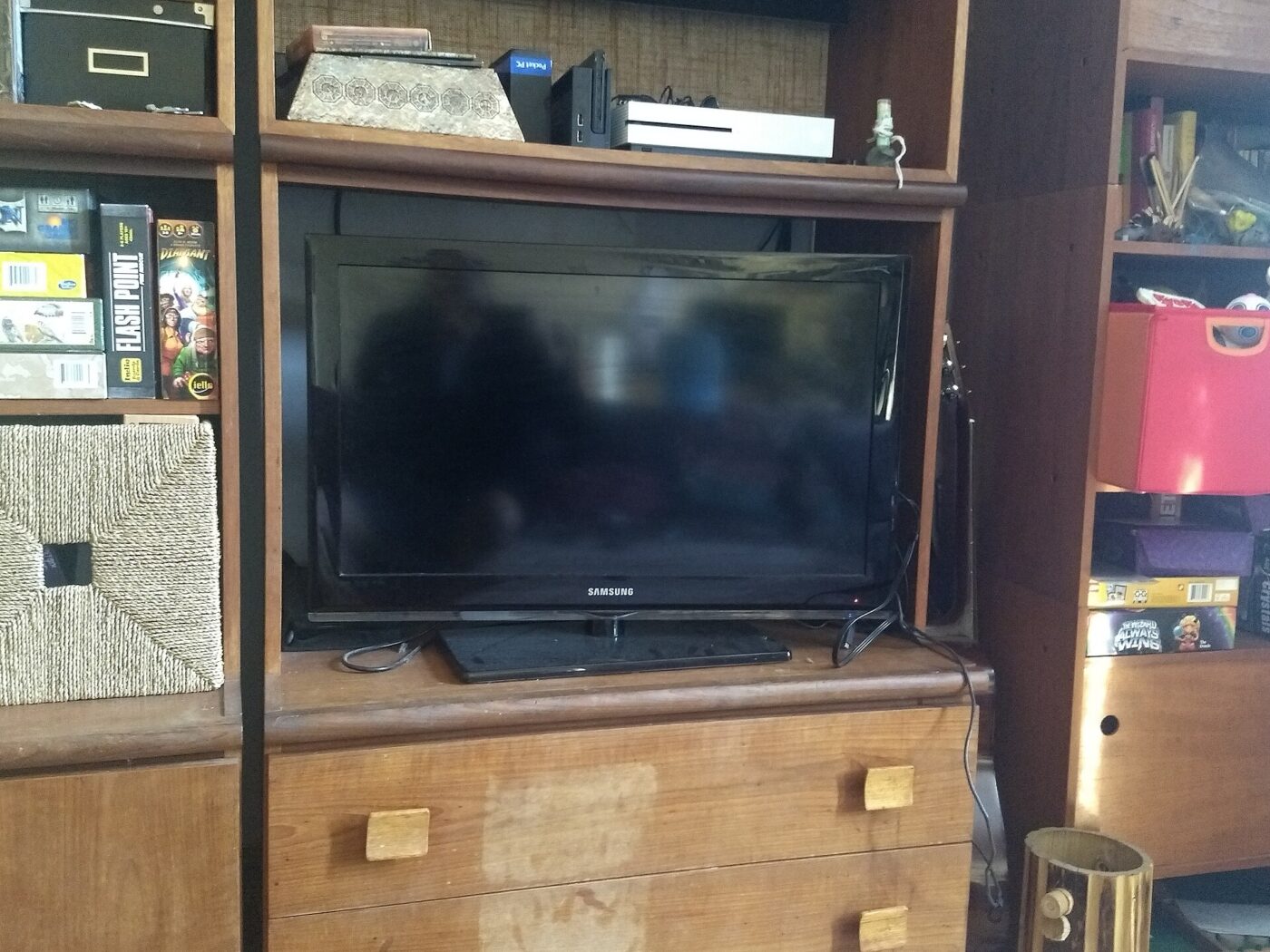 A flat-screen television on top of a wooden dresser in a bedroom.