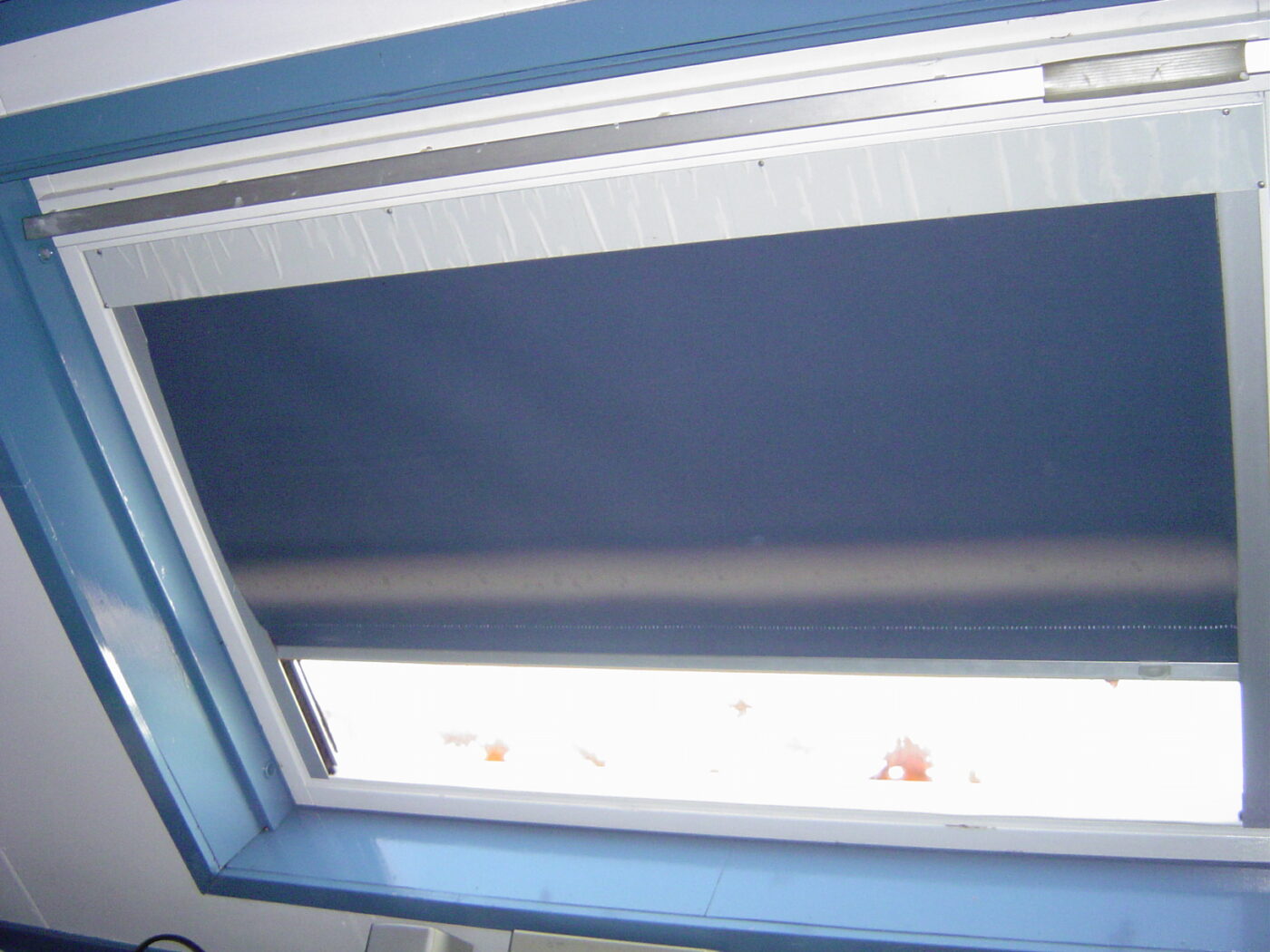 A striped roller blind partway down over a window.