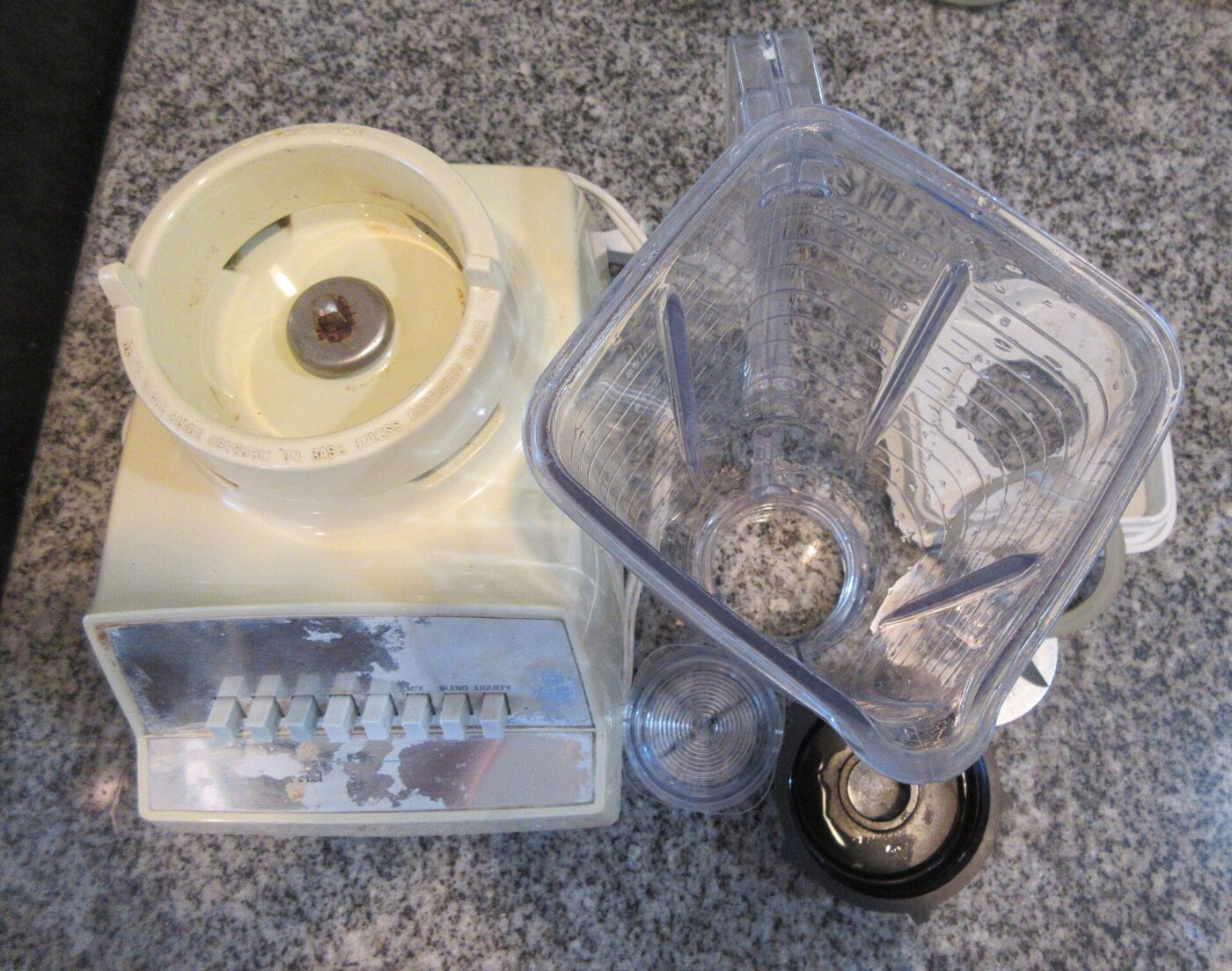 An Osterizer blender taken apart: jar, blade assembly and motor base.