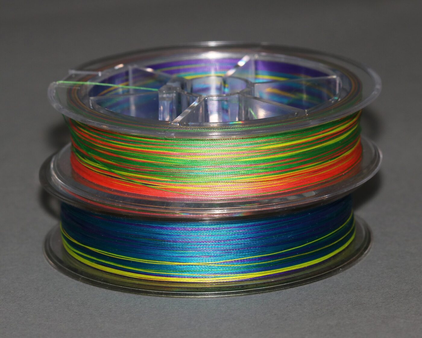 Close-up of a spool wrapped in multicolored braided fishing line strands.