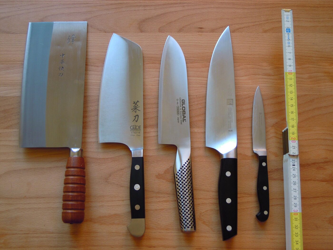 Chef's knives of different profiles laid out beside a paring knife.
