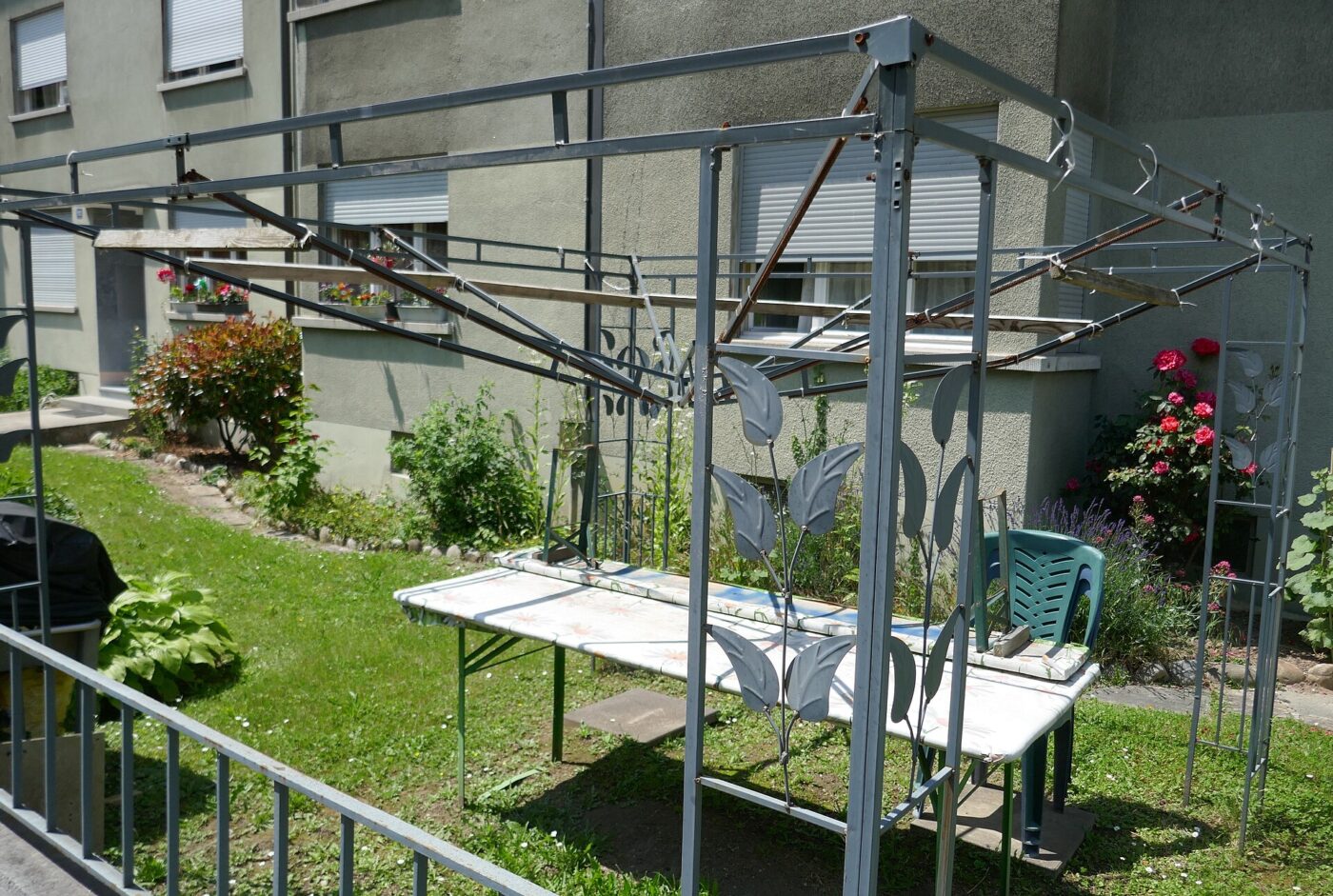 Collapsed, twisted metal frame of a canopy tent lying on pavement.