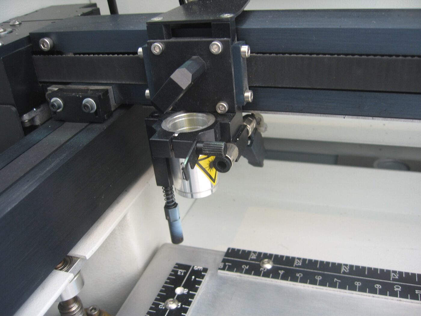 Close-up of an open laser engraver's rail system and cutting head.