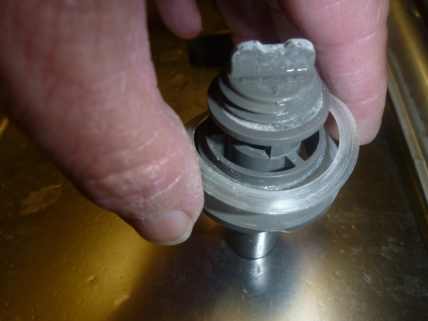 A part removed from a dishwasher during disassembly. Limescale builds up on components like this in hard-water areas.