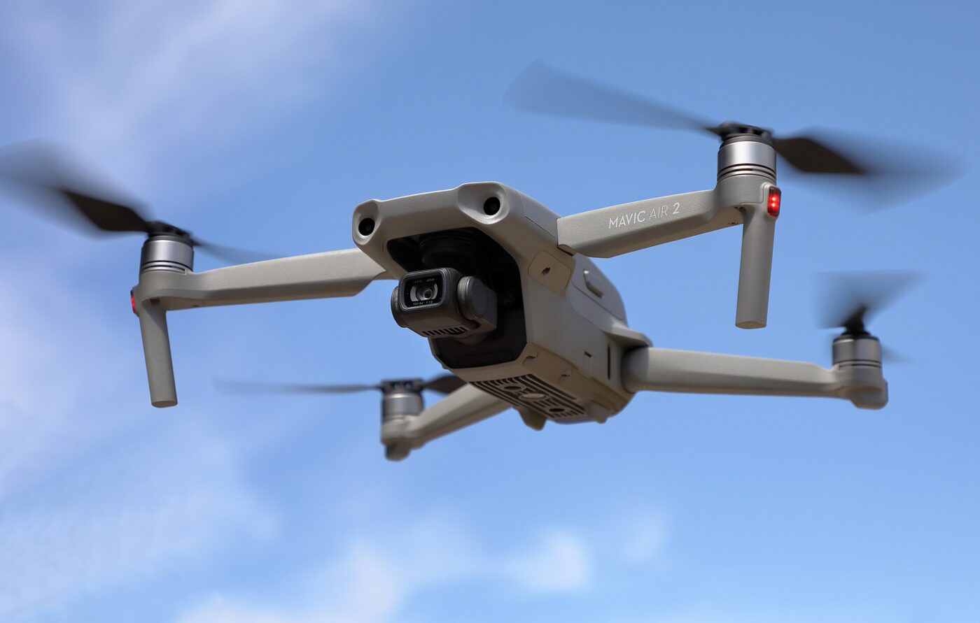 Gray DJI Mavic Air 2 quadcopter drone flying against a clear blue sky.