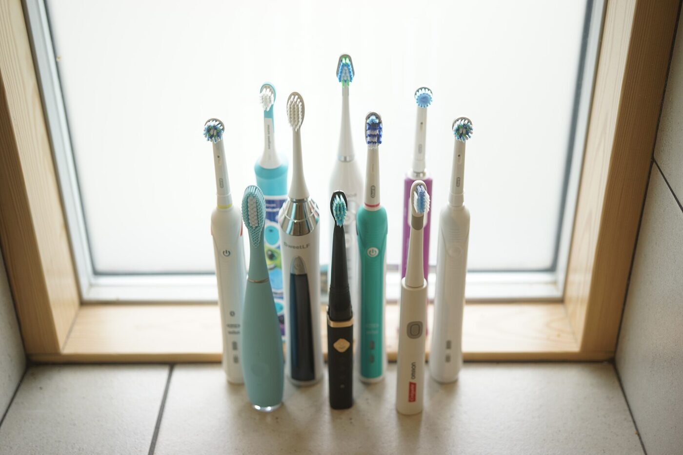 Electric toothbrushes lined up on a windowsill.