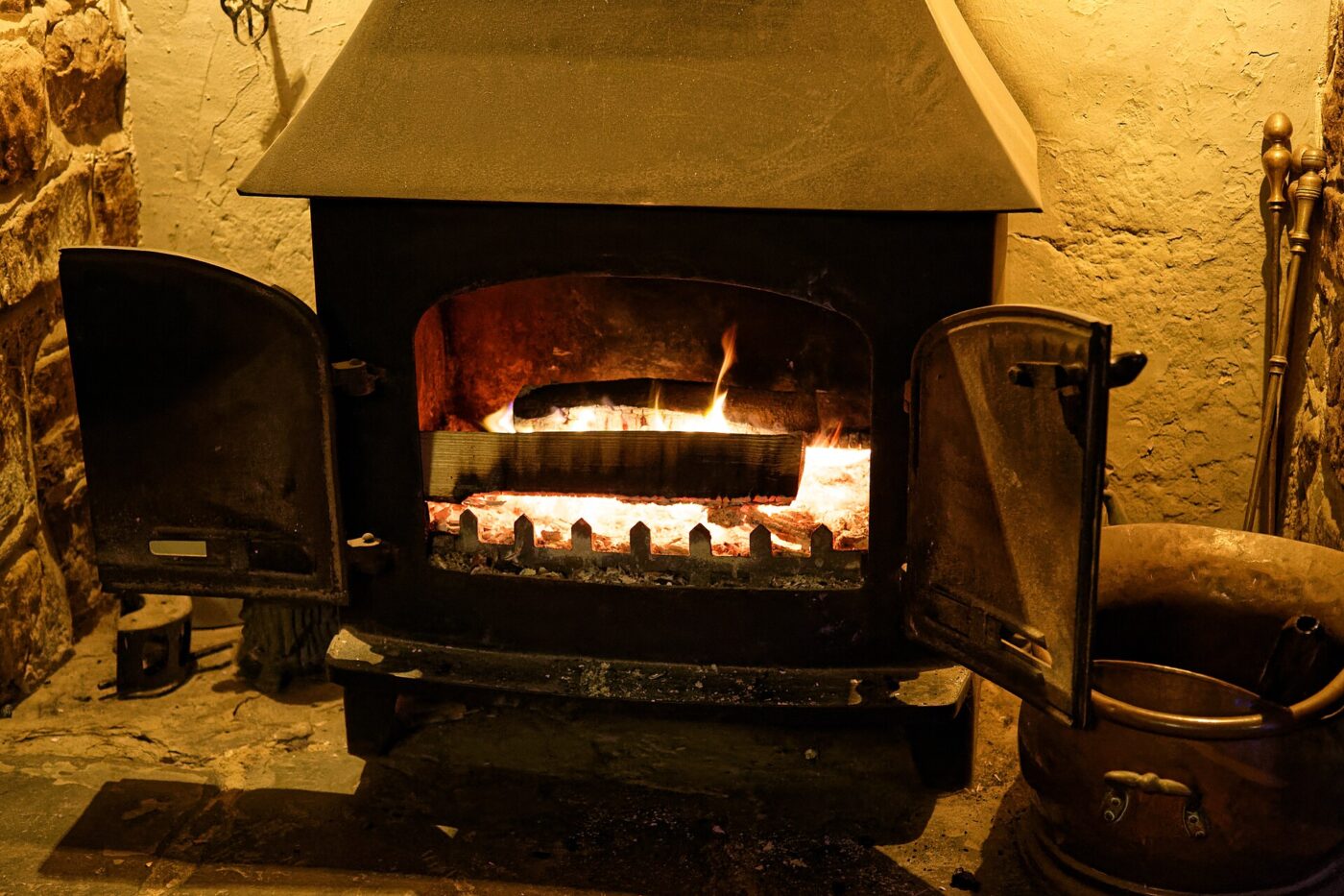 Black stove insert installed in a brick fireplace, chimney pipe visible overhead.