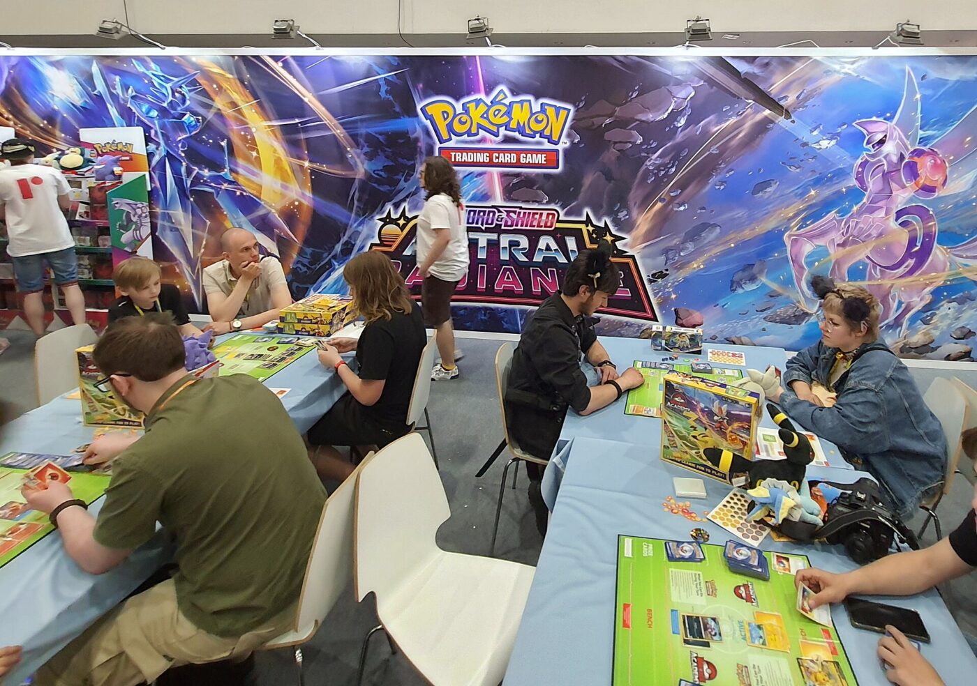 People playing the Pokémon Trading Card Game at convention tables.