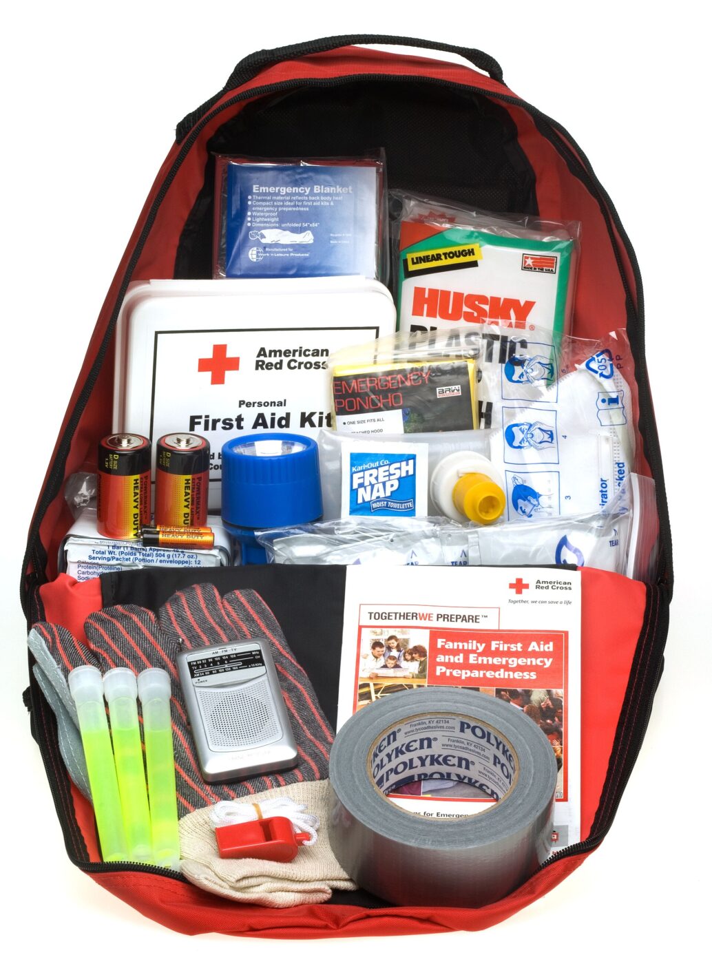 Open backpack showing an American Red Cross first aid kit box, tape, batteries and other emergency supplies.