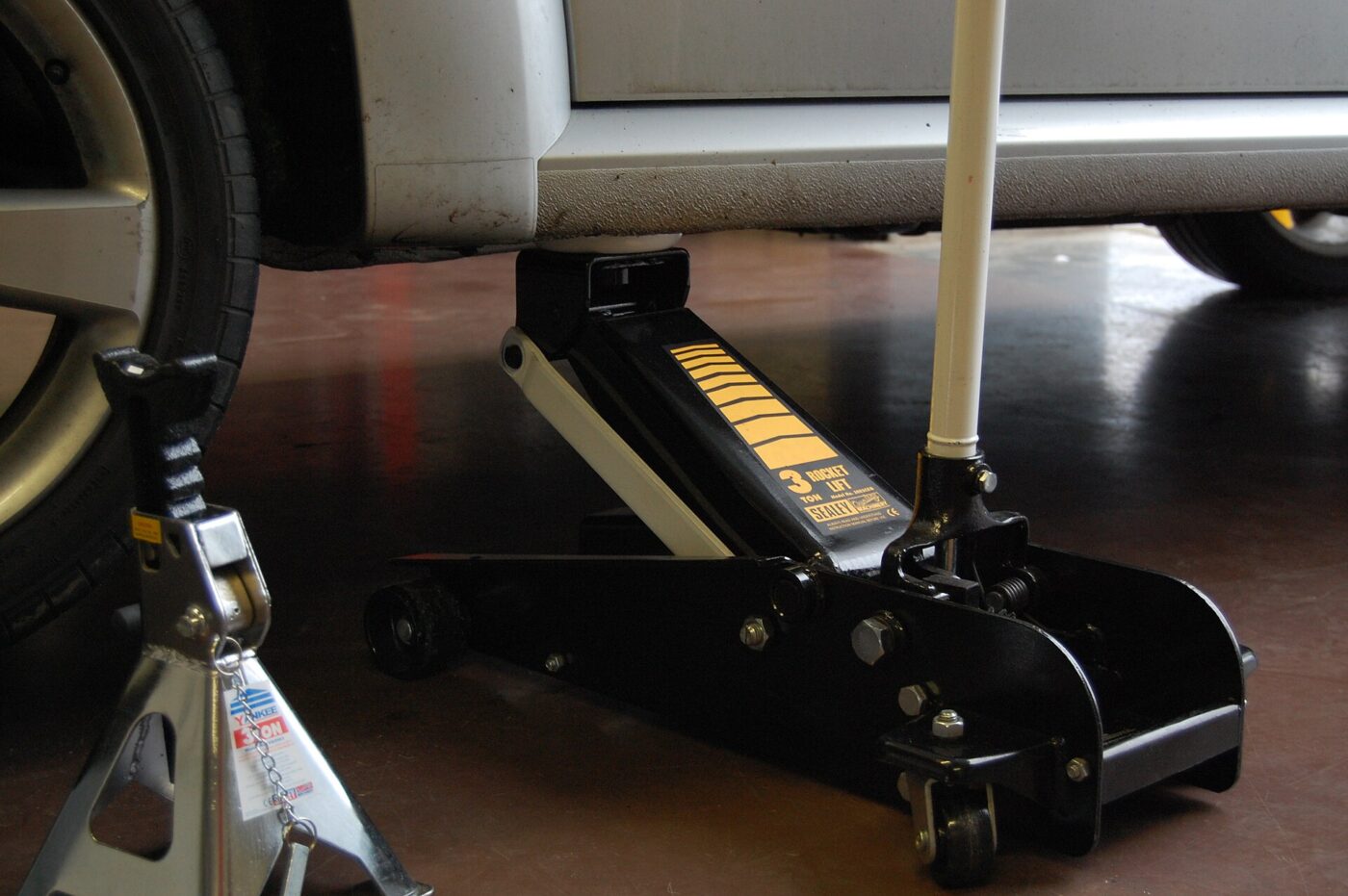 A hydraulic floor jack beside a jack stand.