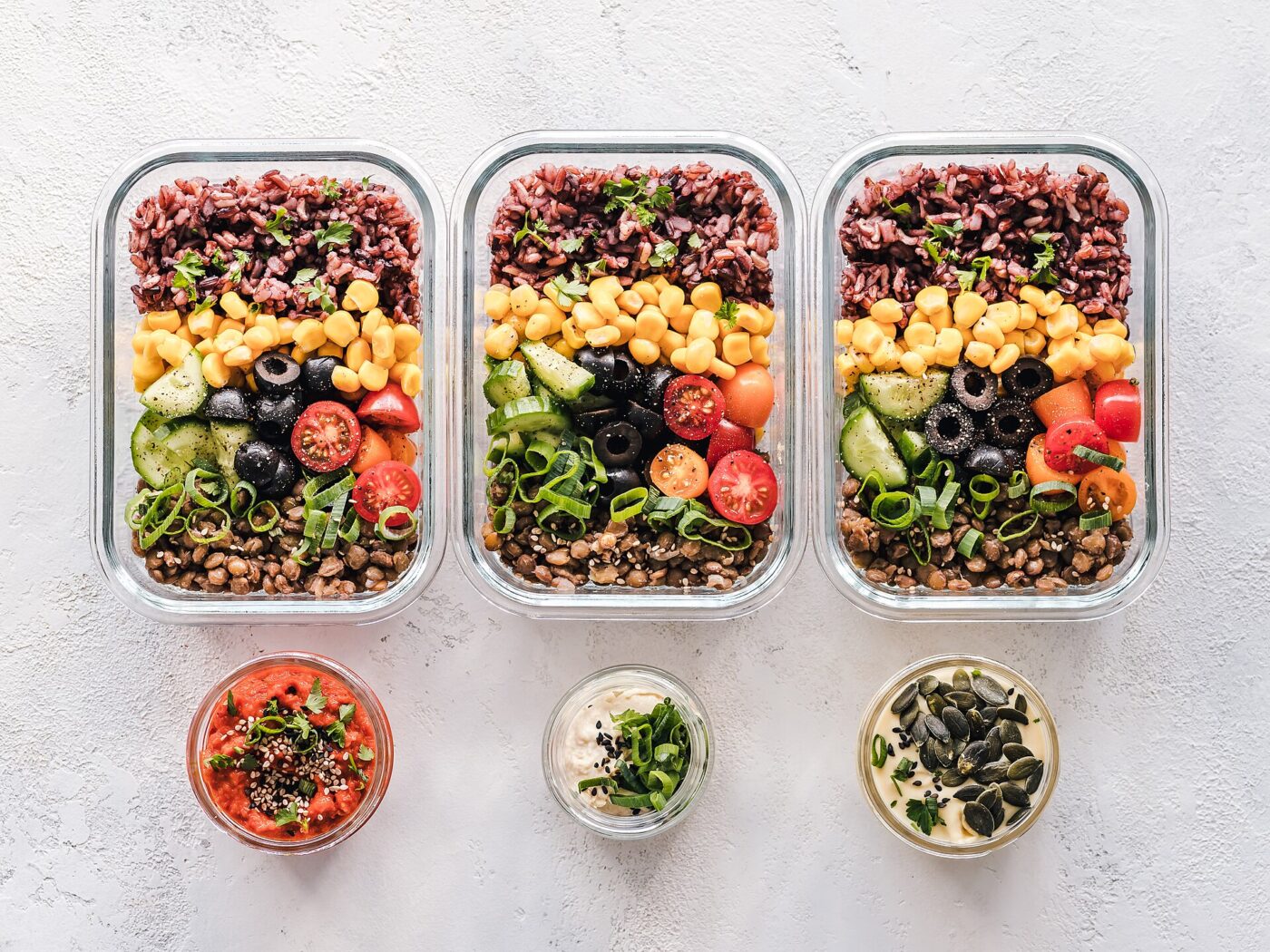Glass meal-prep containers with clip-lock lids, filled with food.