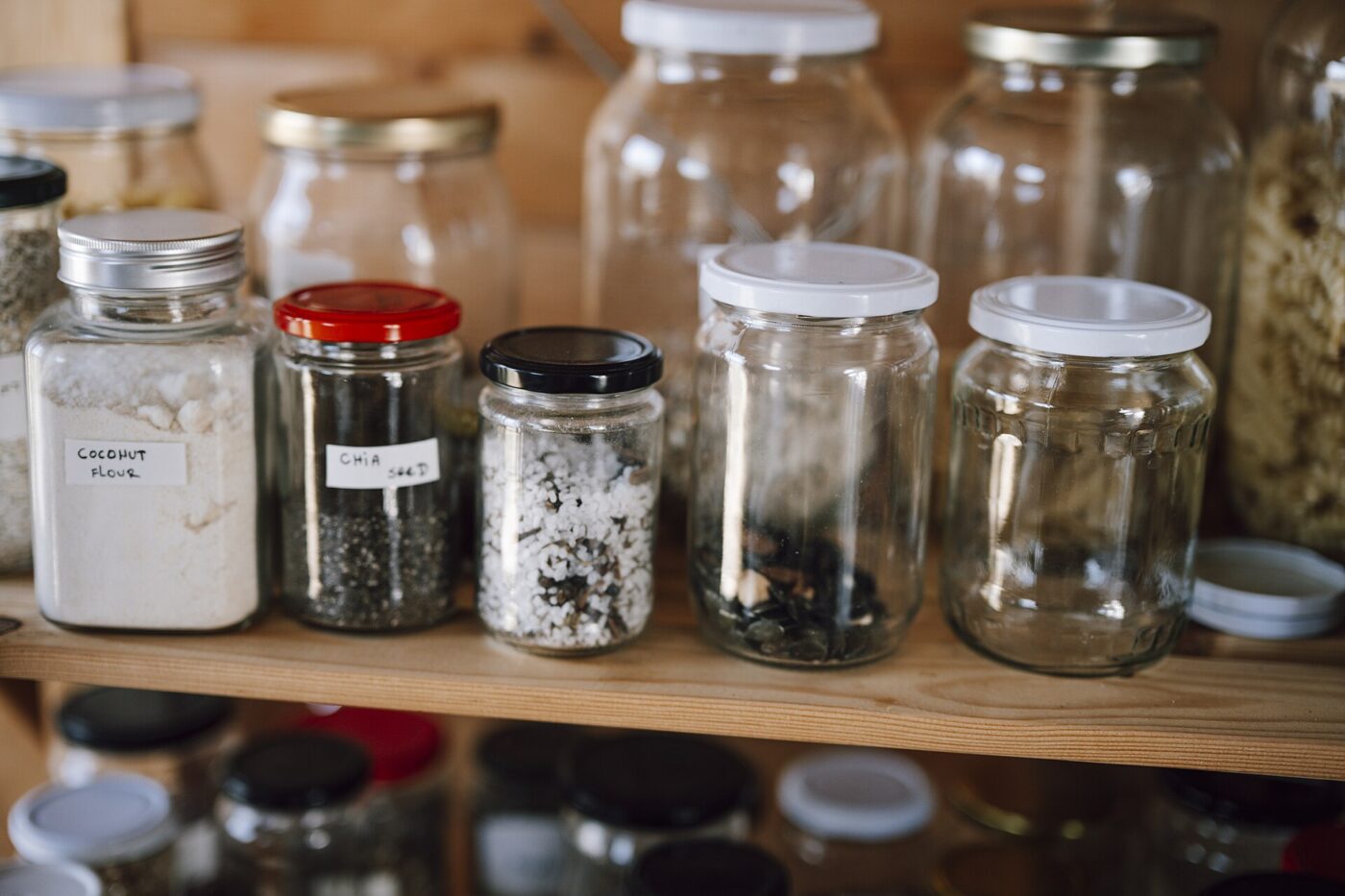 Dry food stored in glass jars and bottles in a kitchen pantry.
