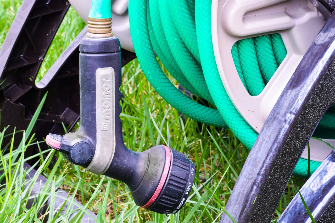 A hose reel with a spray nozzle hanging from it.