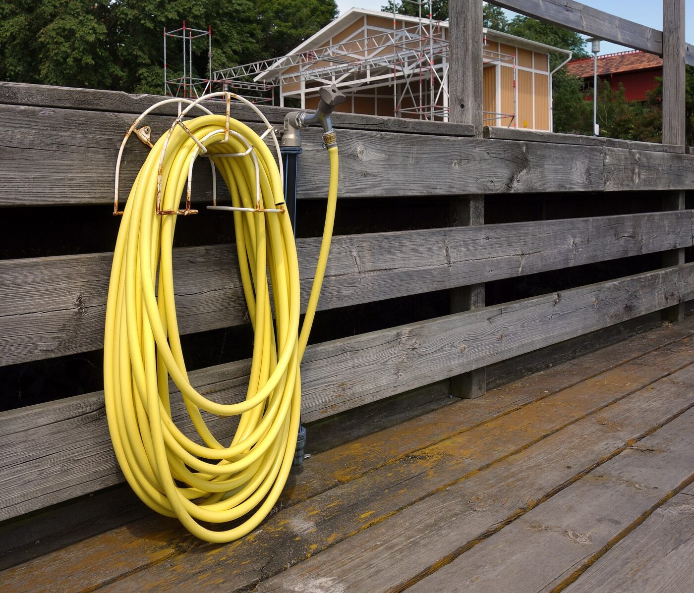 A coiled yellow hose on a deck railing.