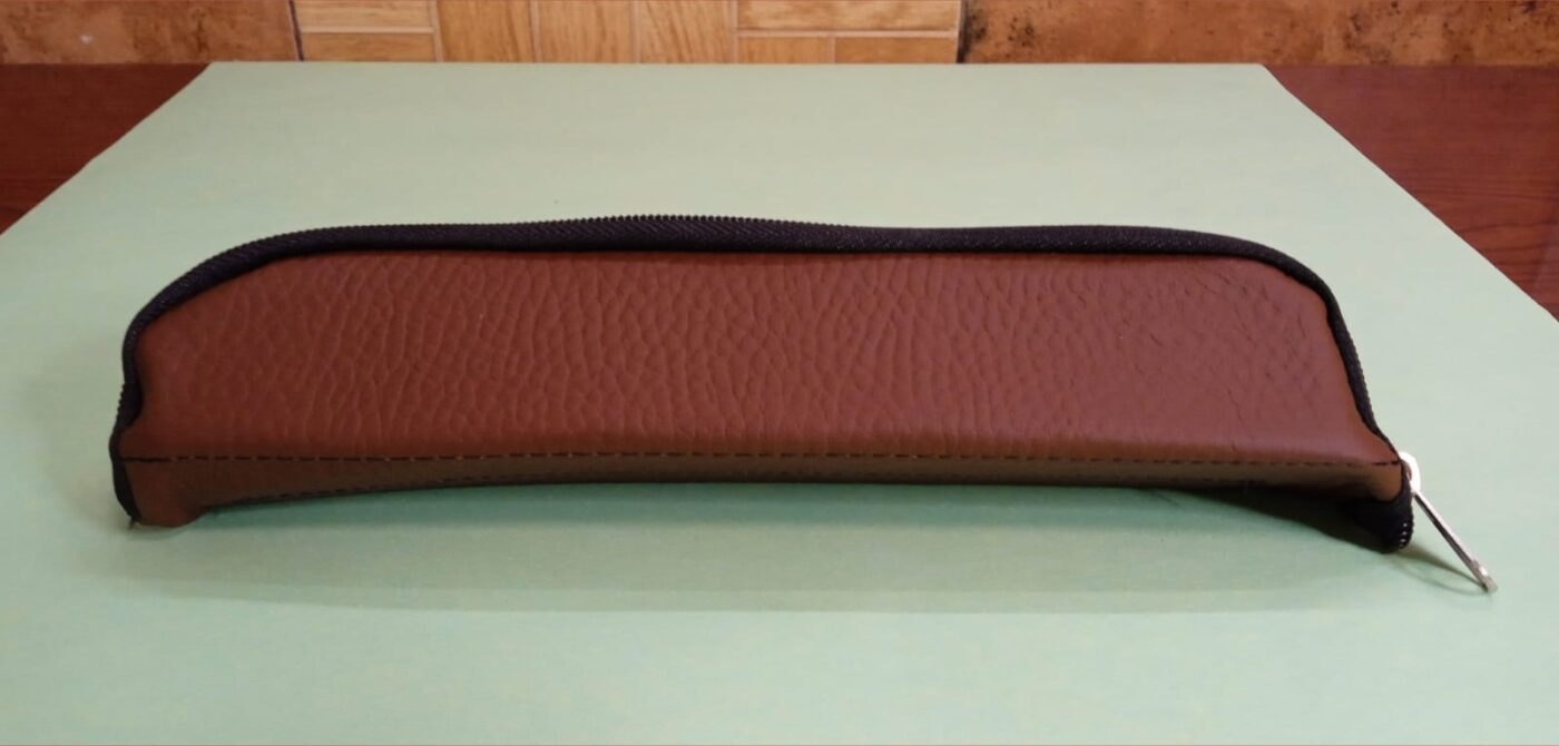A closed reddish-brown leather pouch, its grain texture clearly visible.