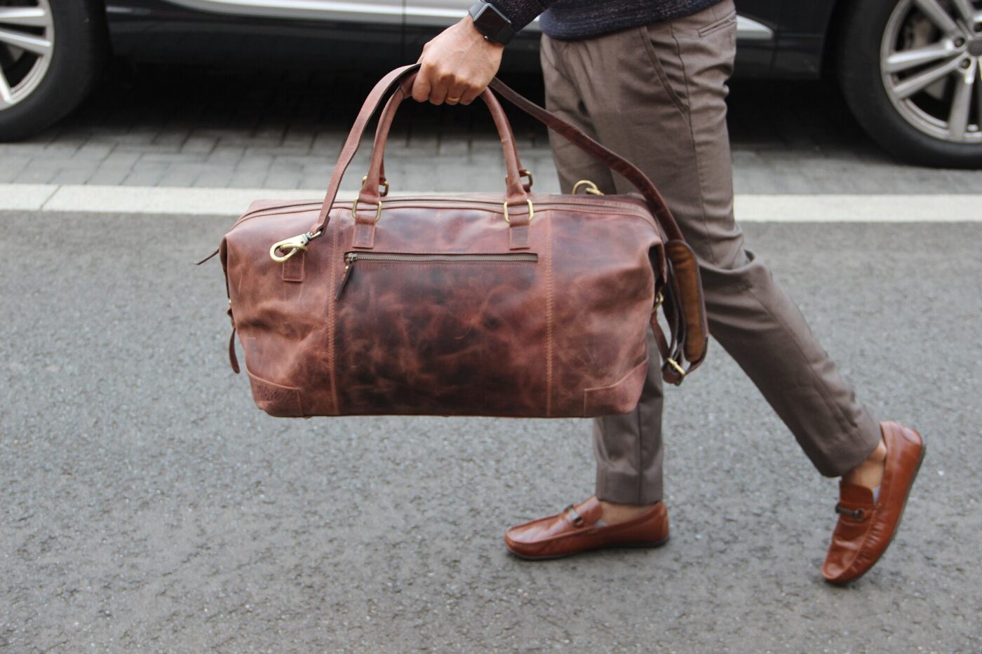 A brown full-grain leather duffel bag, its natural hide grain clearly visible.
