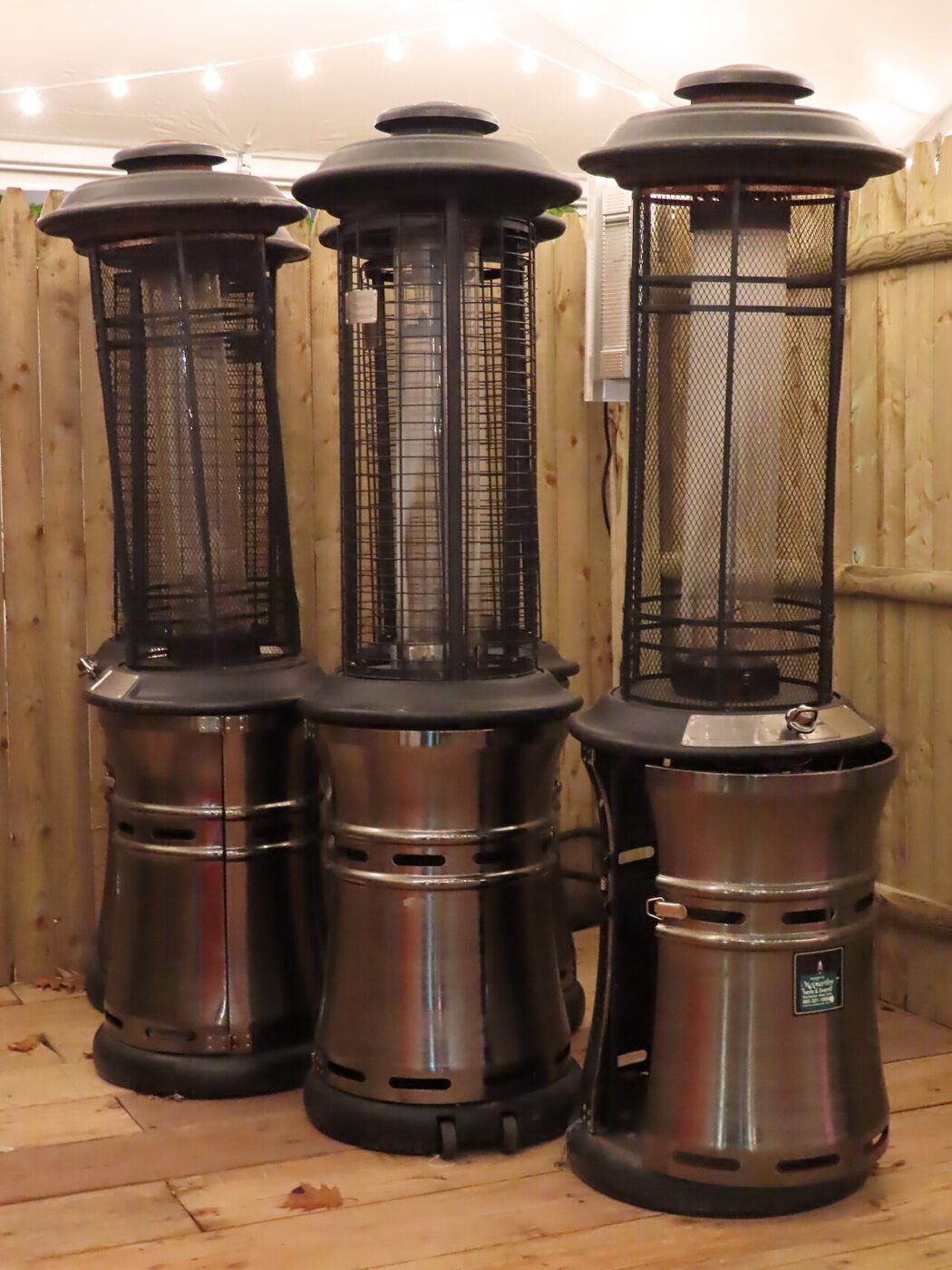 Three freestanding propane heaters set up outdoors.