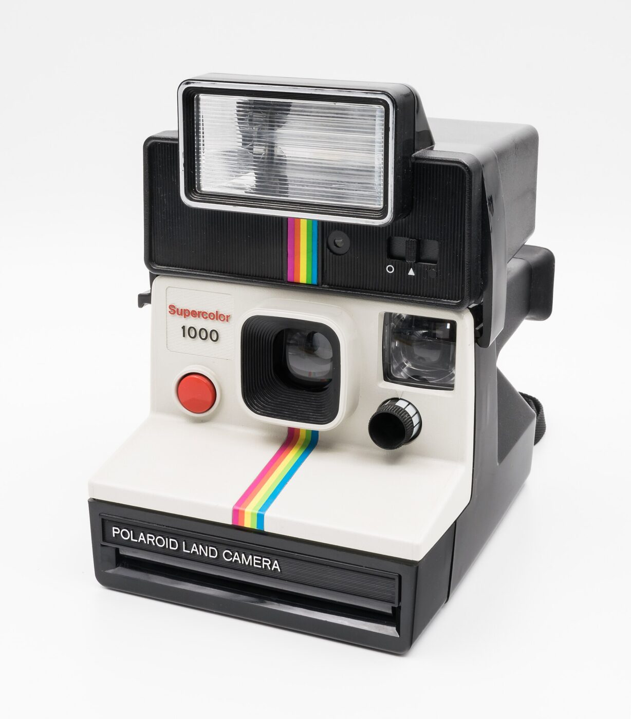 A boxy white and black Polaroid instant camera with a rainbow stripe.