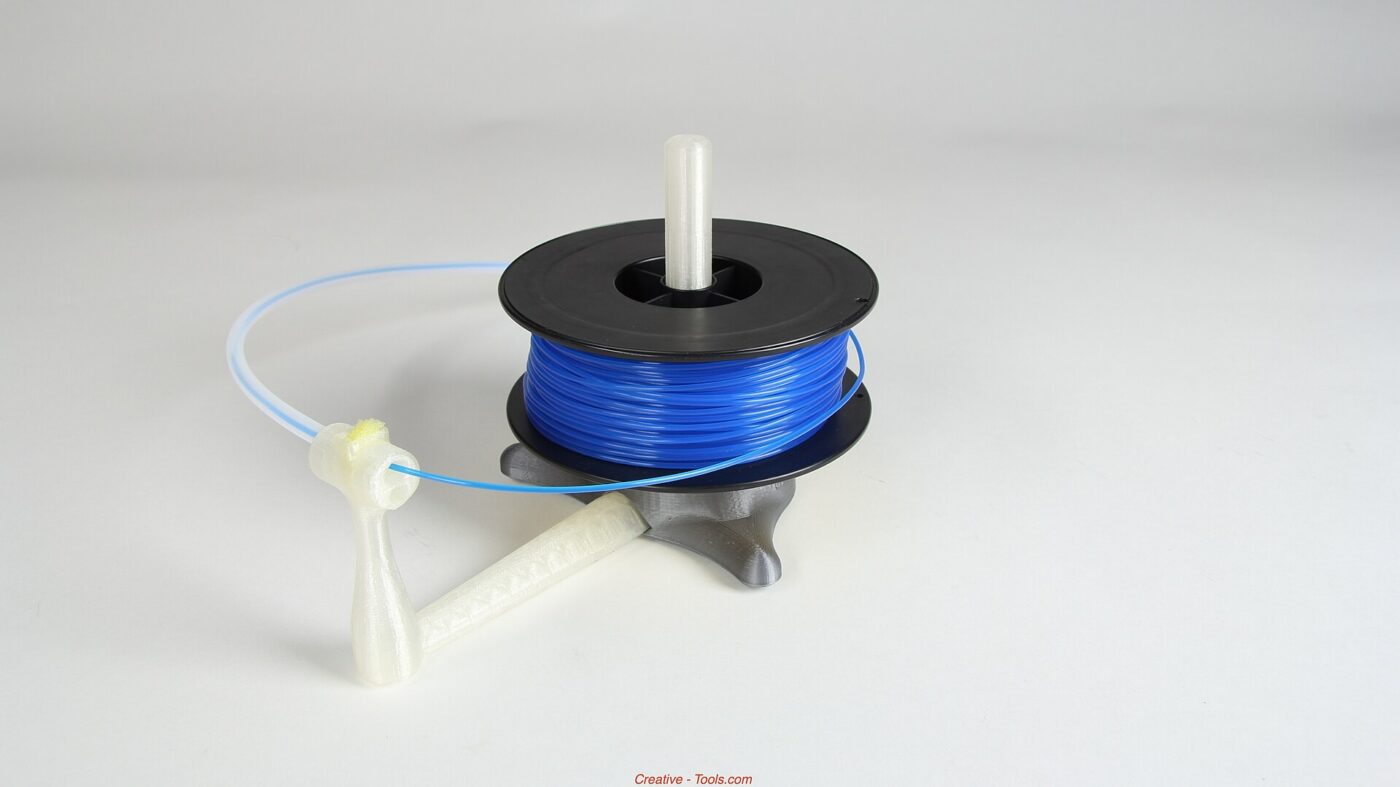 Close-up of a 3D-printed plastic stand with visible stacked layer lines and a filament spool.