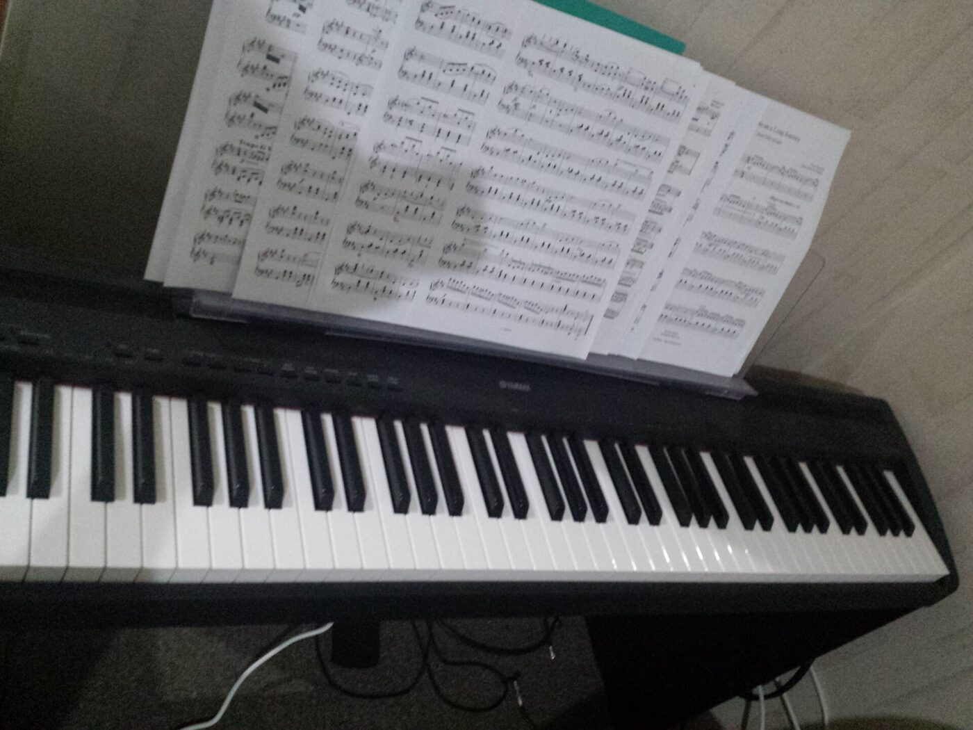 Full-size 88-key digital piano keyboard with a sheet of music propped on the music stand.