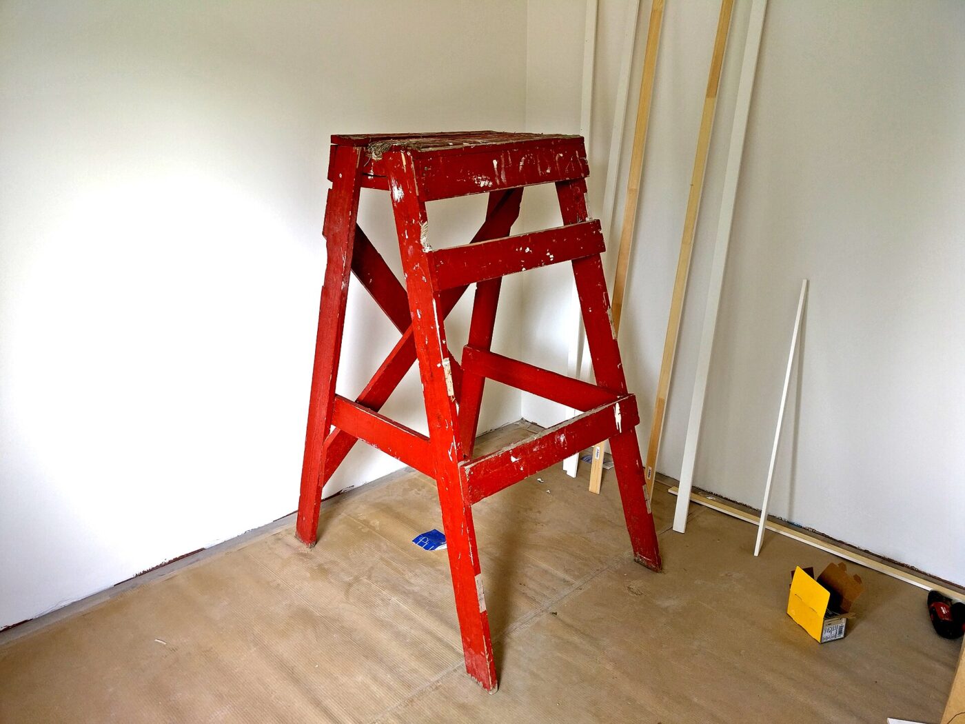 A wooden step ladder painted red.