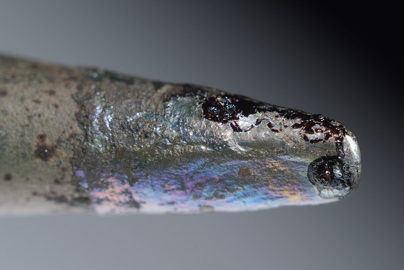 Macro view of a soldering iron tip with molten solder pooled at its point.