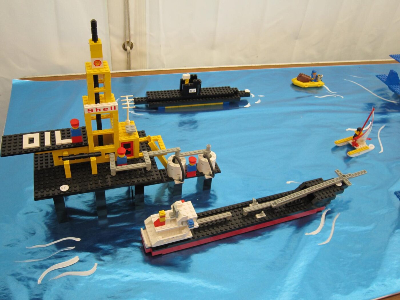 A colorful LEGO oil rig and fuel tanker ship set displayed on a blue baseplate.