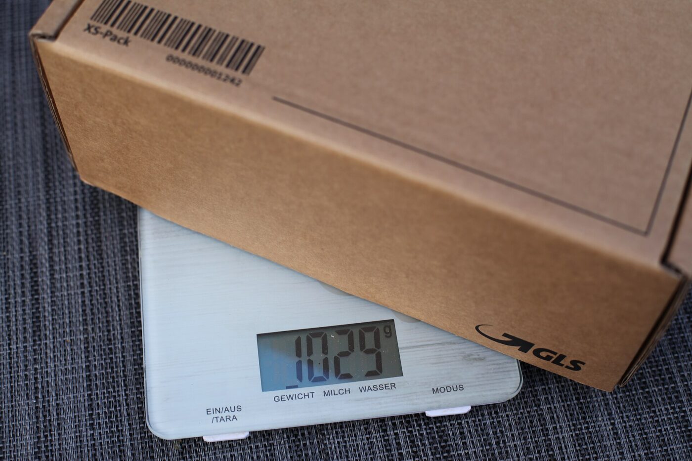 Digital kitchen scale weighing a small box, screen showing the reading.