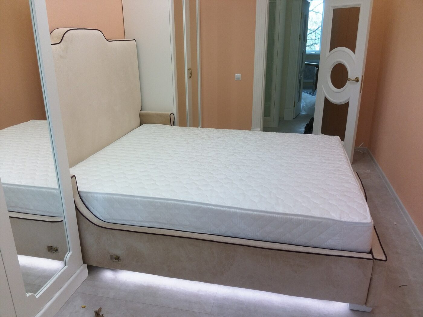 A plain white mattress on a wooden bed frame.