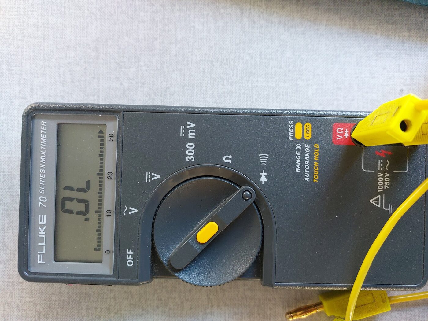 A digital multimeter connected with test leads, its screen reading OL.