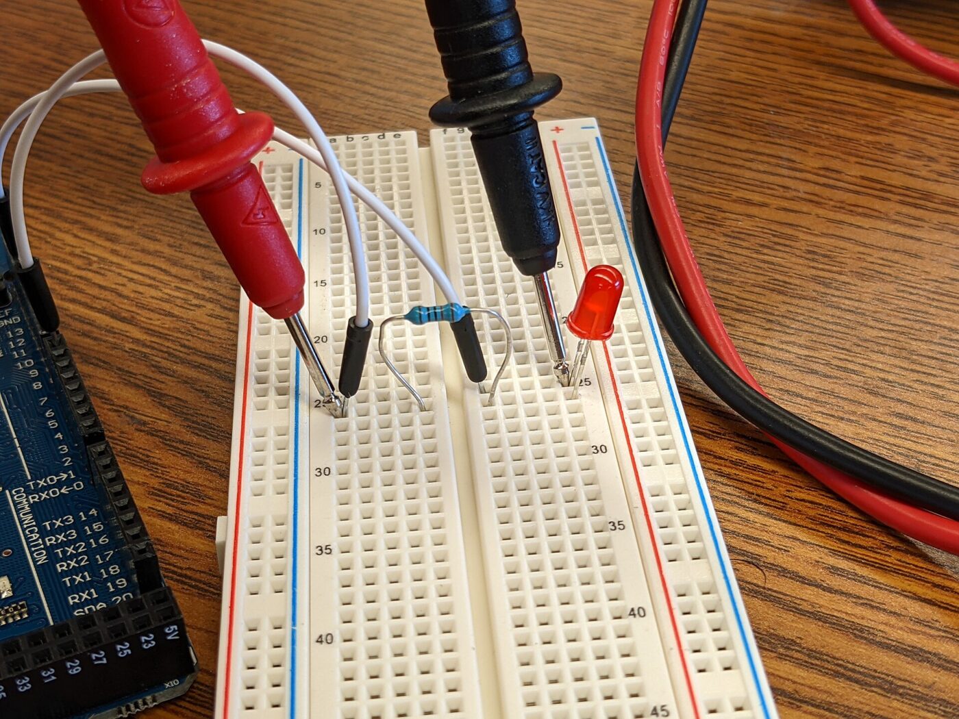 Multimeter probes on a breadboard: low-voltage work, where CAT ratings barely matter.