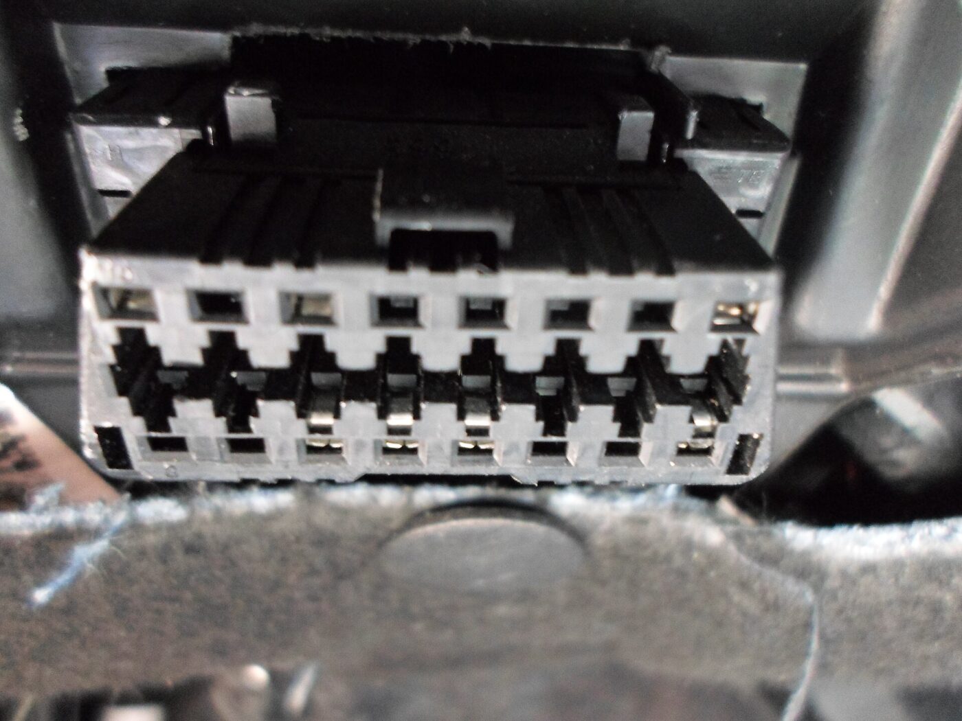 The OBD-II diagnostic port under a car's dashboard.