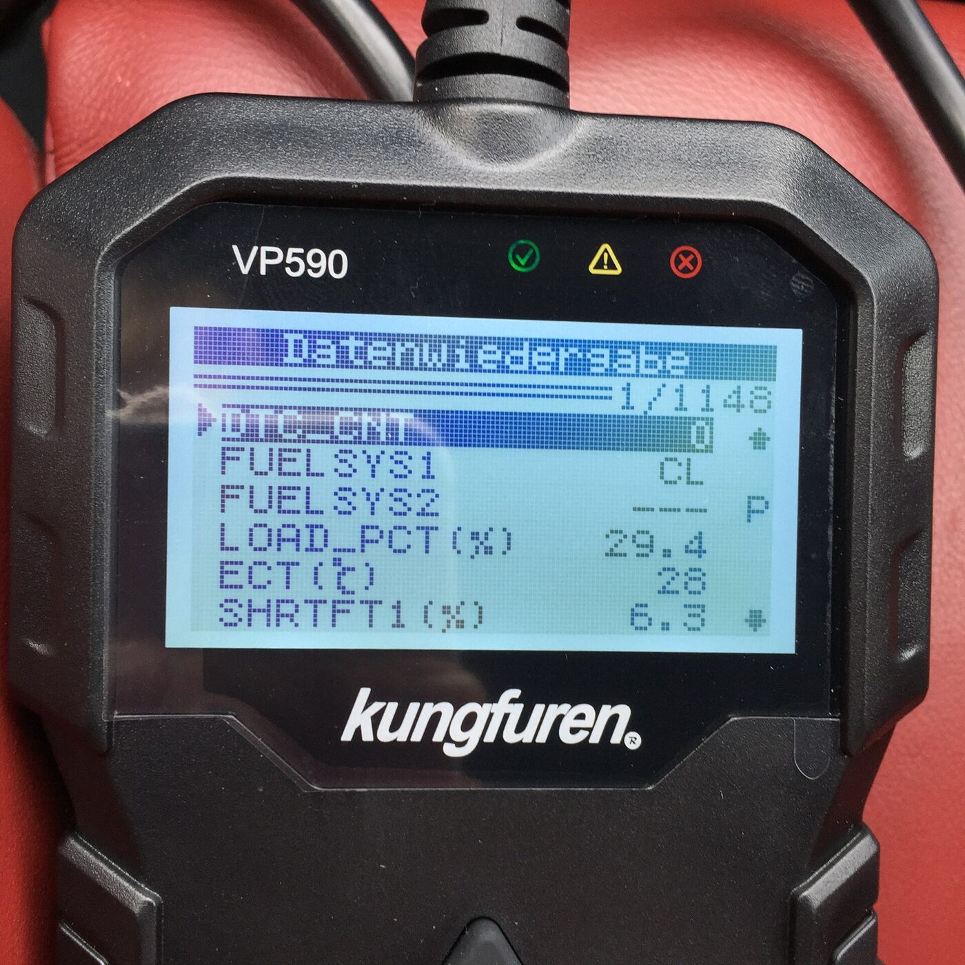A handheld OBD-II scanner displaying live diagnostic data on its screen.