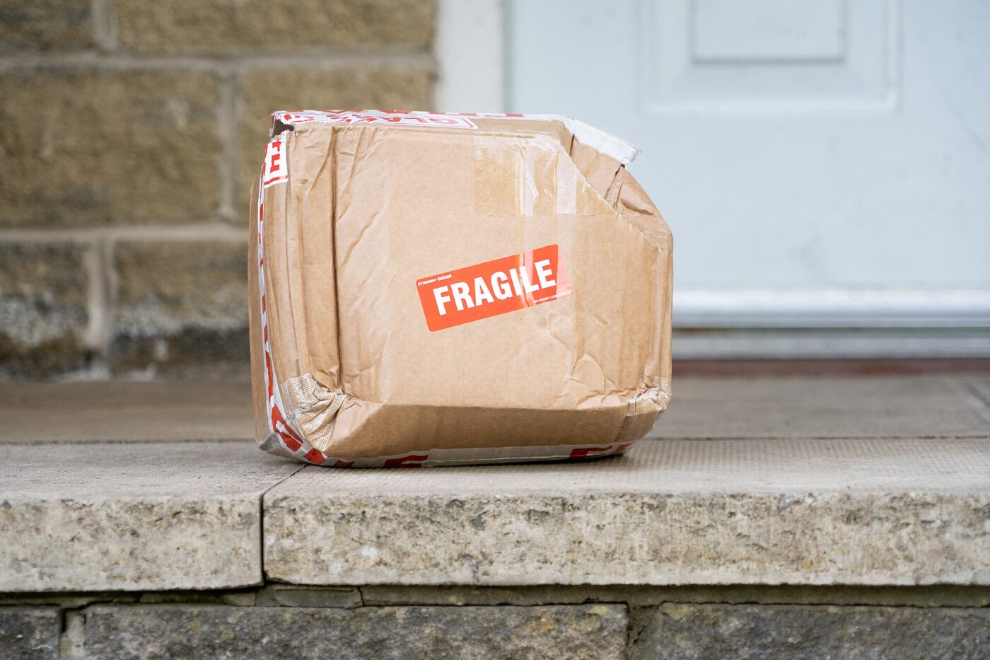 A taped cardboard box with a fragile sticker sitting on a doorstep.