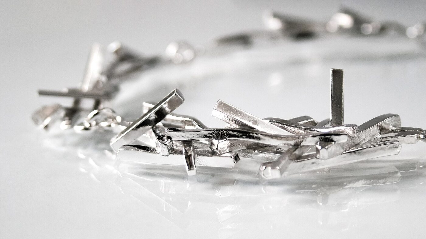 A handmade silver necklace, seen from the side.