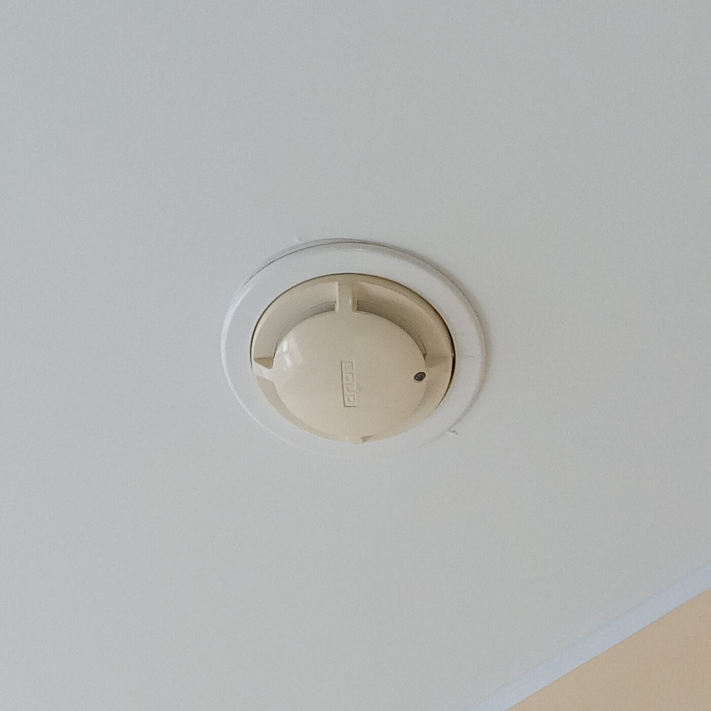 A smoke detector mounted in the middle of a room ceiling.