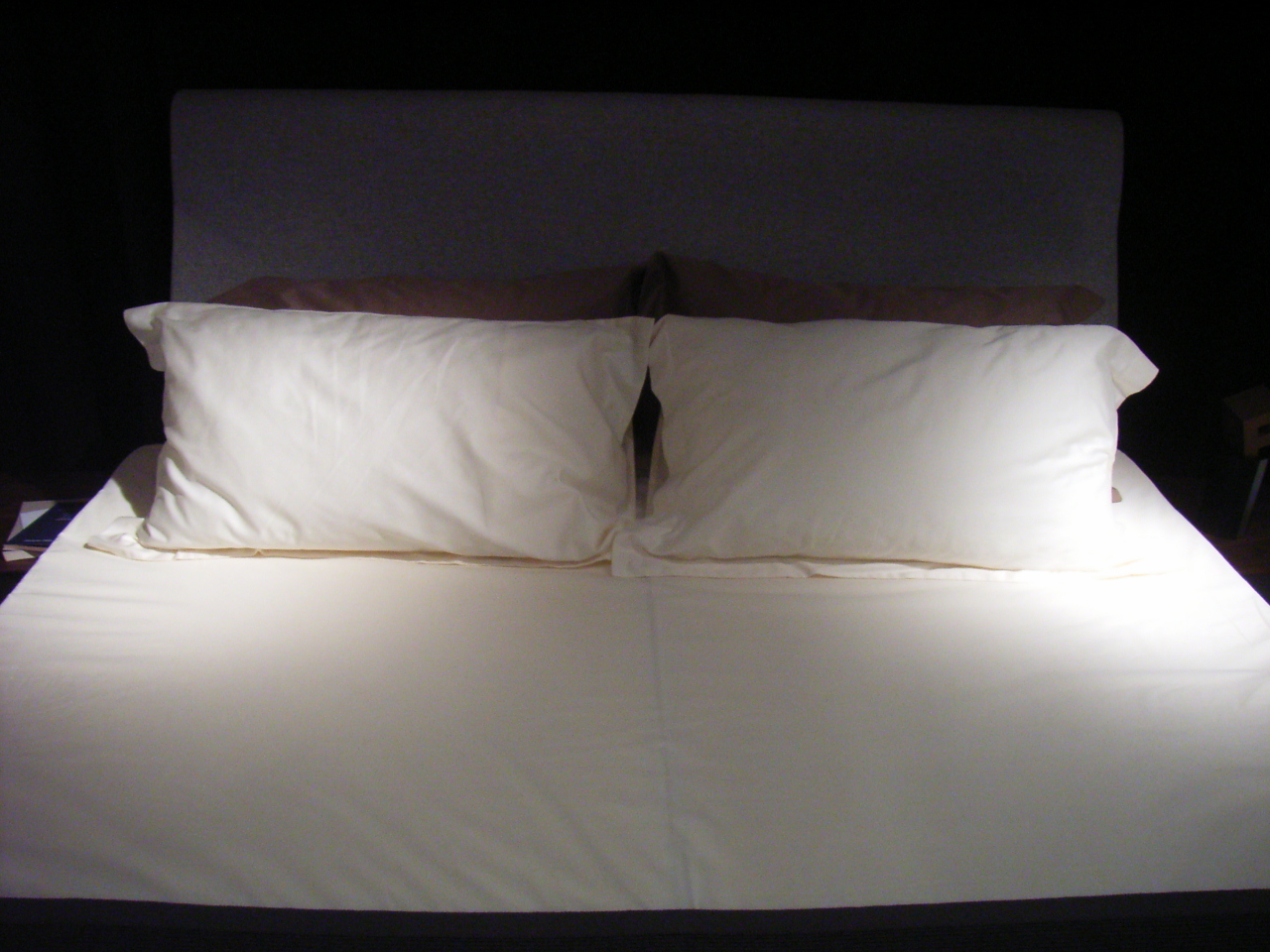 A bed made up with white pillows.