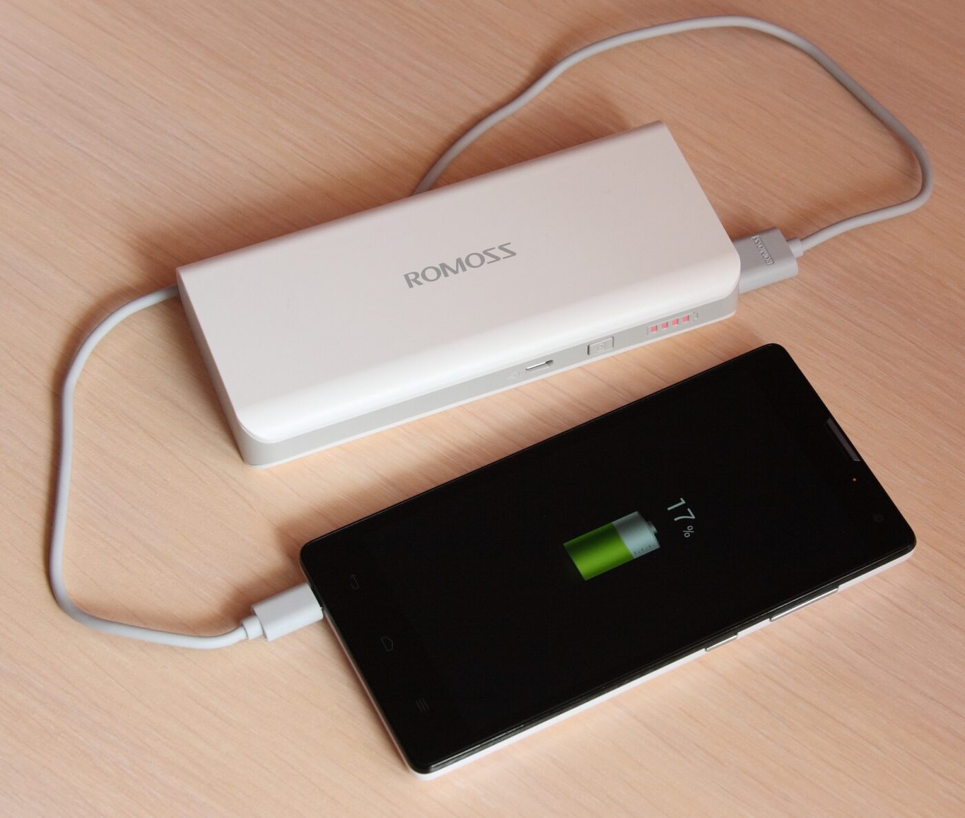 A power bank charging a phone. The mAh figure on the label is measured at the cells, not at the USB port.