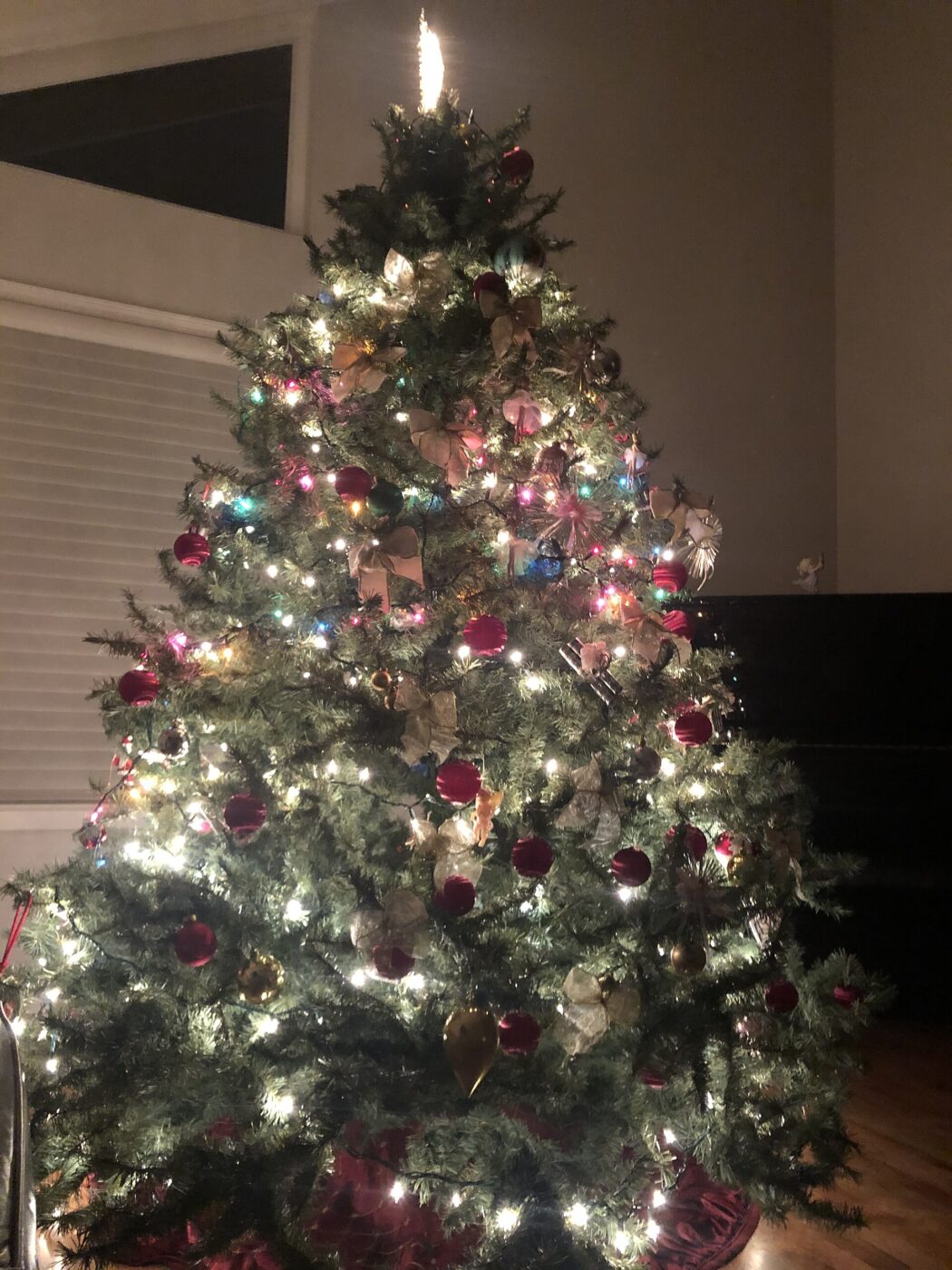 A decorated artificial Christmas tree lit with integrated string lights in a living room.