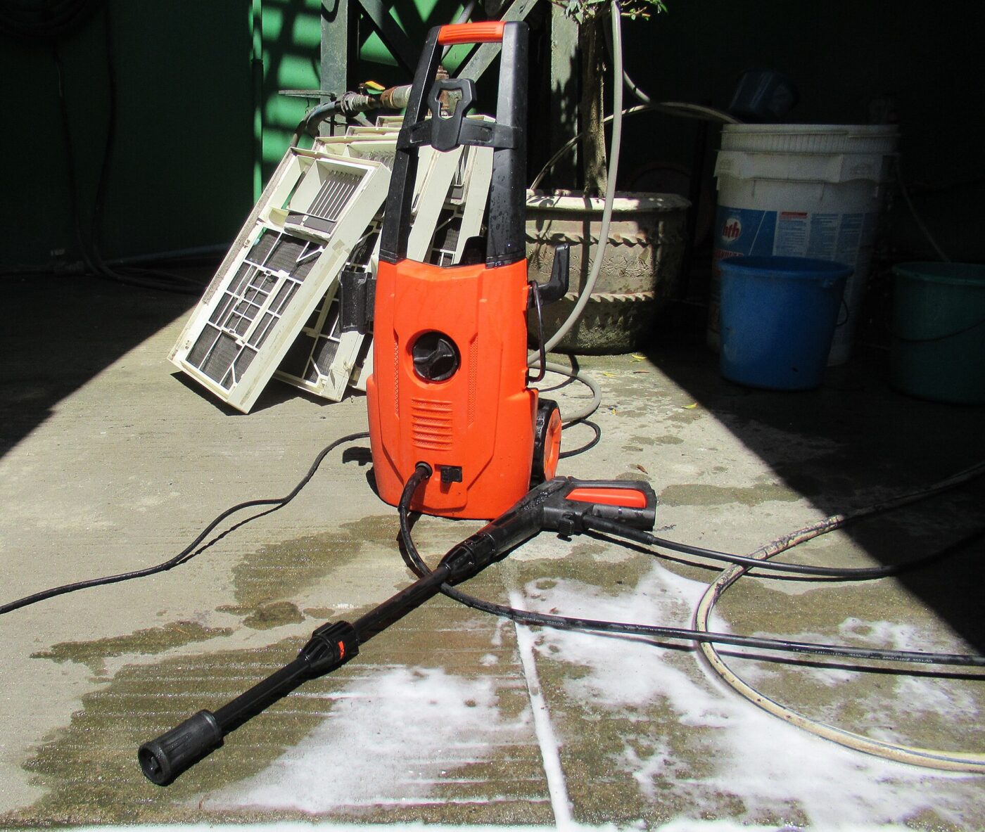 An orange electric pressure washer standing in a home garage.