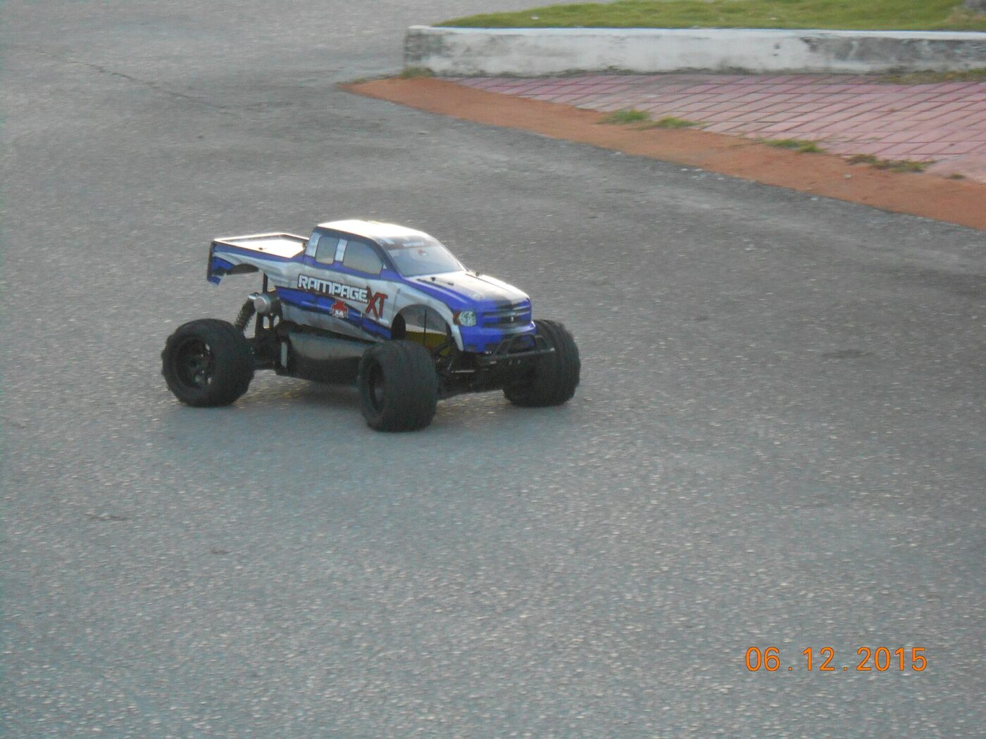 A blue and white radio-controlled truck parked on a paved surface outdoors.