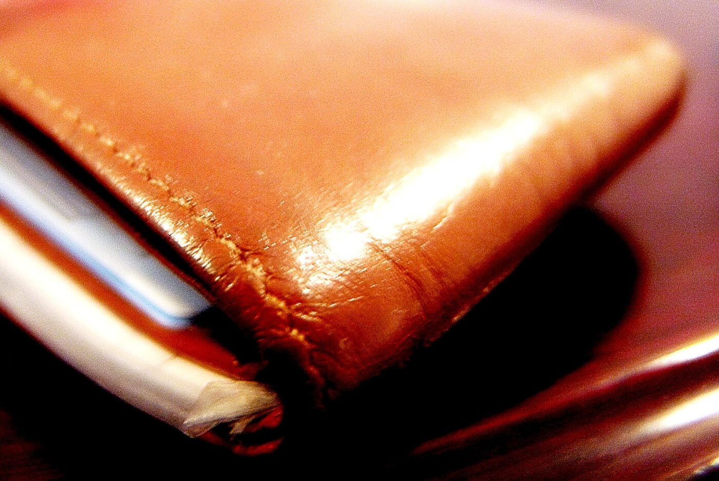 A leather wallet with a card tucked into one of its slots.