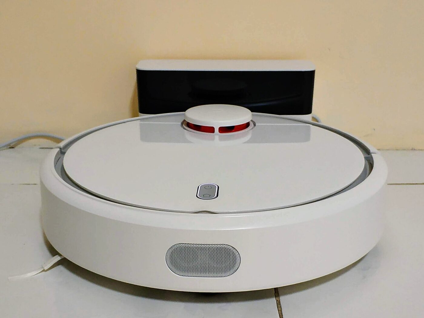 A white robot vacuum cleaner on a hardwood floor.