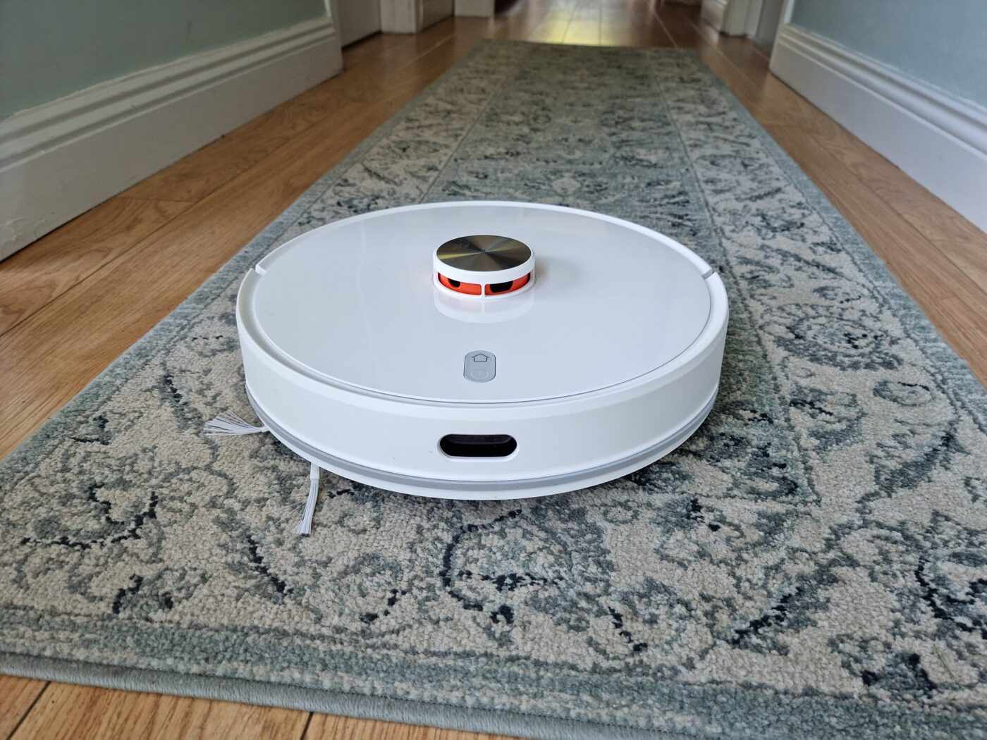A lidar robot vacuum on a hallway runner rug.